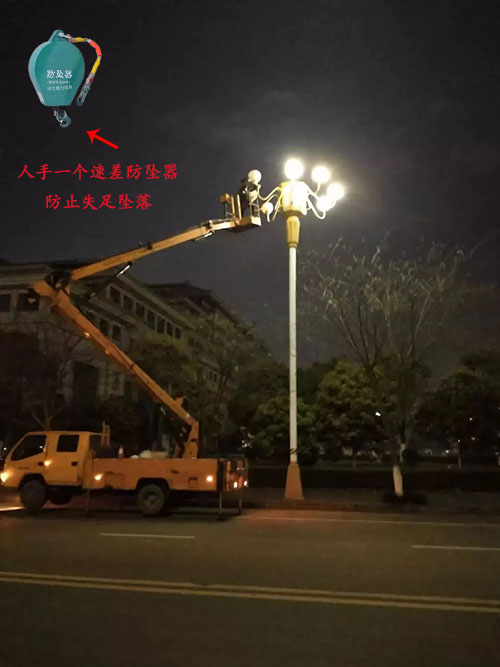 夜晚工人佩戴速差防墜器進(jìn)行高空維修路燈